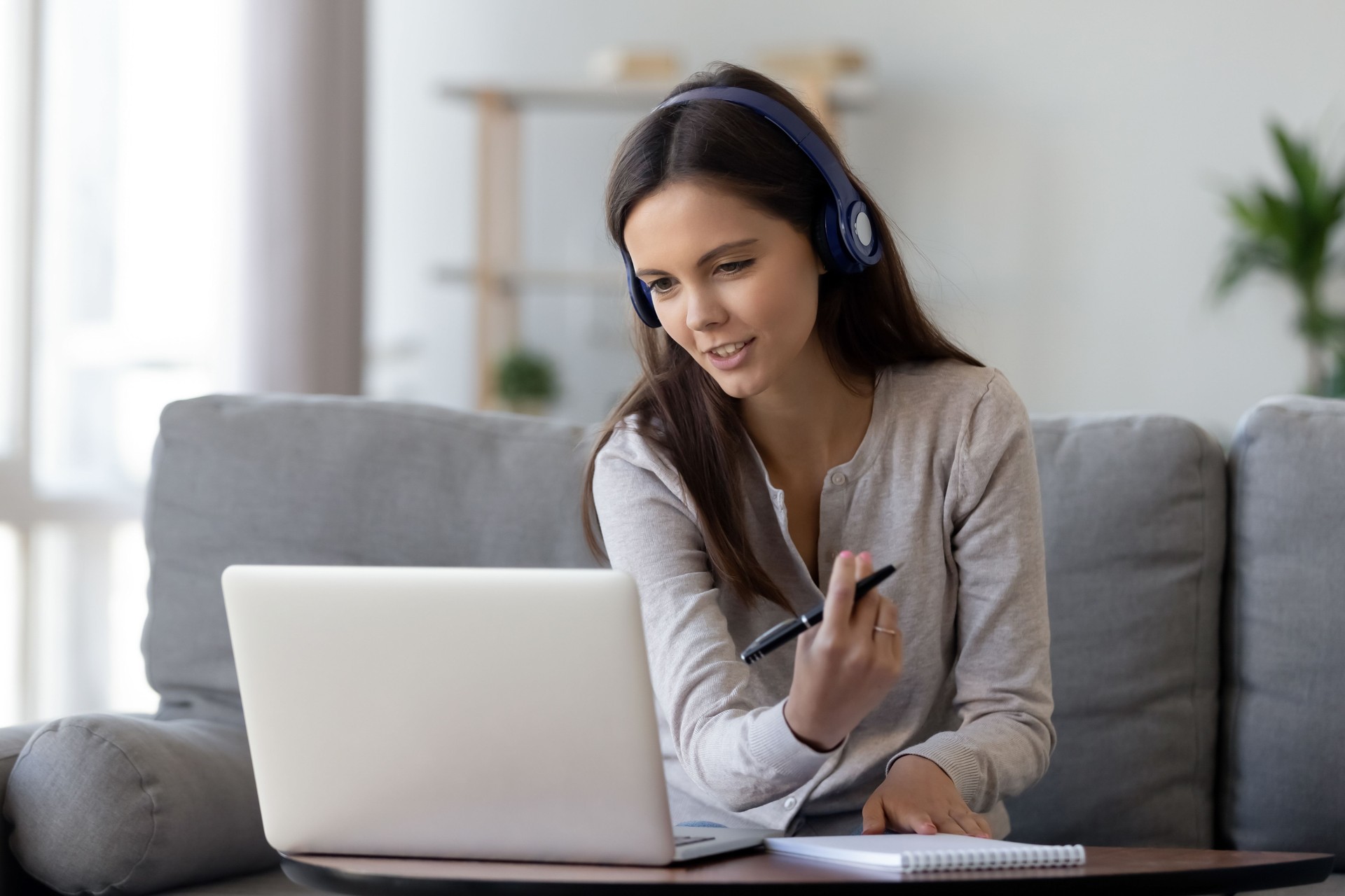 Happy young woman in headphones speaking looking at laptop to assist with online notarization services